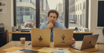 Entrepreneur dans un espace de coworking réel réfléchissant entre deux options de statut juridique, assis à un bureau avec dossiers et documents dans une scène naturelle et authentique.